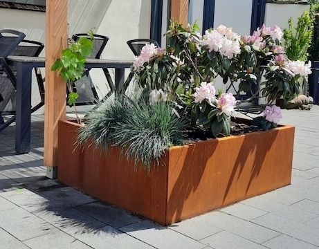 Roestige plantenbak zonder bodem in de tuin